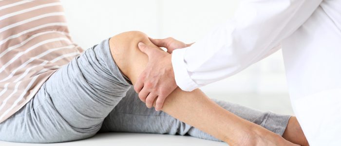Doctor examining mature woman with joint pain in clinic