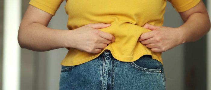 Woman body fat belly. Obese Woman with fat upset about her belly. Fat woman with tight clothing worried about weight diet lifestyle concept